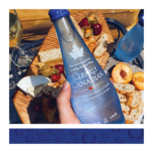 Clearly Canadian Sparkling Mineral Water Bottle 325ml Held in Hand in Front of Food & Drink